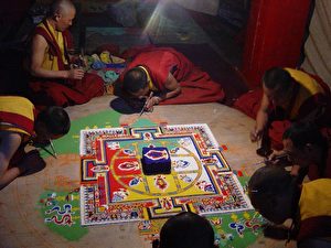Buddhistische Mönche stellen eine Sandmandala her, ein vergängliches Bild vom Universum. (