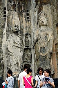 Tourists visit the Longmen Grottoes Buddhist sculptures. Damage to the face of the left-hand statue is clearly visible. (Teh Eng Koon/AFP/Getty Images)