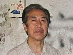 Professor Sun Wenquang vor der Wand seines Wohnhauses in der Shandong Universität. Auf der Wand beleidigende Sprüche wie „Vergewaltiger Sun Wenquang“, „Verräter“, „Schurke Sun Wenquang“. (The Epoch Times)