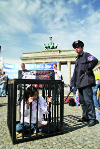 Archivbild - Eine Szene der Verfolgung und Folter wird dargestellt, der Praktizierende der spirituellen Bewegung Falun Gong durch das chinesische kommunistische Regime unterworfen sind. Diese außergewöhnliche Demonstration fand vor dem Brandenburger Tor in Berlin statt.