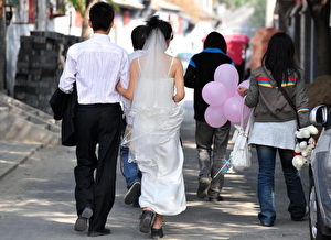 Auf dem Weg zum Fotoshooting lange vor der Hochzeit geht dieses Paar durch die alten Hutong Gassen in Peking.