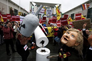 Atomkraftgegner demonstrierten am Dienstag mit einer Angela-Merkel-Puppe und einer Puppe, die einen Vertreter der Atomlobby symbolisiert und die mit Kettensägen ein fünf Meter hohes Windrad-Modell zerstören vor dem Kanzleramt in Berlin gegen die geplante Laufzeitverlängerung für Atomkraftwerke.
