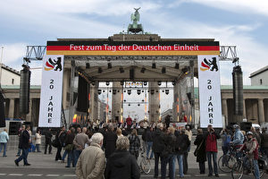 Passanten stehen vor dem für das Fest zum 20. Jahrestag der Deutschen Einheit geschmückten Brandenburger Tor in Berlin. An diesem Wochenende wird mit zahlreichen Veranstaltungen der 20 Jahrestag der Wiedervereinigung begangen.