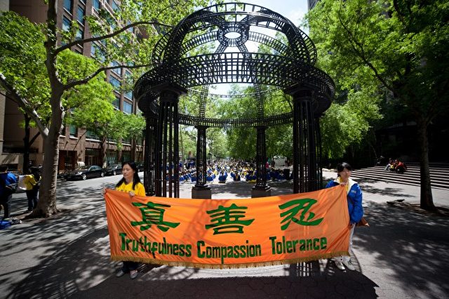 Falun Gong-Praktizierende halten ein Spruchband mit den Grundprinzipien dieser spirituellen Praxis: Wahrhaftigkeit, Barmherzigkeit und Toleranz.