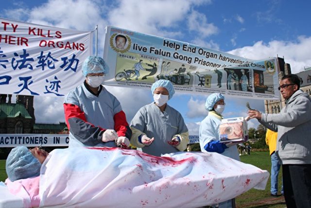 Falun Gong-Praktizierende inszenieren den Organraub in China auf einer Kundgebung in Ottawa, Kanada.