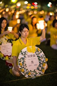 Falun Gong-Praktizierende gedenken der Toten, die die Verfolgung in China gefordert hat. Im Hintergrund sitzen Hunderte in Reihen in vollkommener Stille.