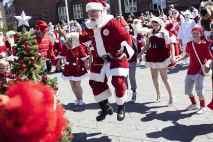 Weihnachtsmänner tanzen um den Christbaum