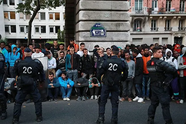 Migrants stand in front of French gendarmes while they are evicted from a makeshift camp, on July 22, 2016 in Paris. Between 1,200 and 1,400 people, mostly men, from Eritrea, Somalia and Afghanistan, were in this camp near the metro stations Jaures and Colonel Fabien. / AFP / JACQUES DEMARTHON (Photo credit should read JACQUES DEMARTHON/AFP/Getty Images)