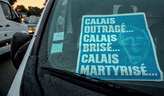 A picture taken on September 5, 2016 shows a banner reading "Calais outraged, Calais broken, Calais martyred" and picturing Charles De Gaulle in a vehicle during a "go-slow" protest lead by truck drivers on the A16 highway from Loon Plage to Calais to ask for the dismantling of the so-called "Jungle" migrant camp in the French northern port city of Calais. French farmers and truckers launched a joint operation on September 5, 2016 to block off main routes in and out of Calais to call for the closure of the sprawling "Jungle" migrant camp there. Around 70 trucks began a "go-slow" on the main A16 motorway -- the main artery for freight and passengers heading for Britain either via the Channel Tunnel or the Calais port. / AFP / PHILIPPE HUGUEN (Photo credit should read PHILIPPE HUGUEN/AFP/Getty Images)