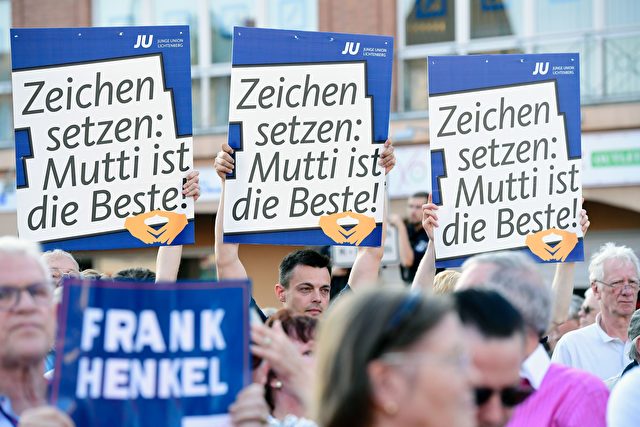 Supporters of German Chancellor Angela Merkel and Christian Democtaric Union (CDU) candidate Frank Henkel hold up placards as they wait for her to arrive for an electoral meeting of the Christian Democtaric Union (CDU) party ahead of the weekend's state elections in Berlin of September 14, 2016. / AFP / TOBIAS SCHWARZ (Photo credit should read TOBIAS SCHWARZ/AFP/Getty Images)