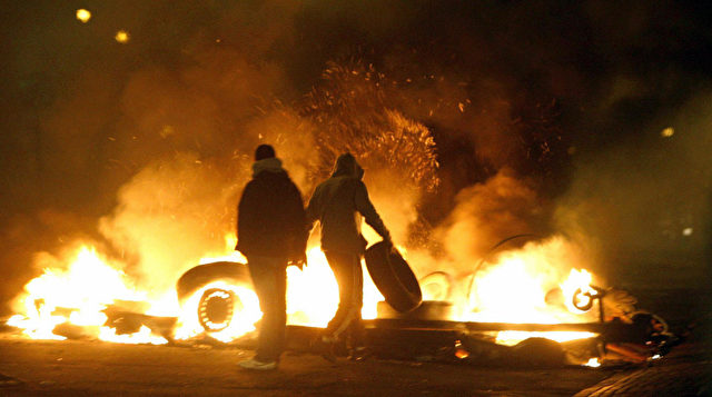 People stand in front of burning barricades on the main road of the Rosengard suburb of Malmo, southern Sweden, on December 18, 2008. Some 100 youths rioted in the southern Swedish town of Malmoe late Thursday for the second straight night, setting cars and garbage bins ablaze and throwing stones at police, police said. Police spokeswoman Ewa-Gun Westford said the troubles were linked to the recent closure of an Islamic cultural centre in Malmoe's heavily-immigrant populated neighbourhood Rosengaard. AFP Photo / Drago Prvulovic / SCANPIX ** SWEDEN OUT ** (Photo credit should read DRAGO PRVULOVIC/AFP/Getty Images)