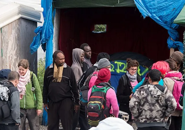 &quot;No borders&quot; movement activists speak with migrants in the so-called 'Jungle' camp in the French northern port city of Calais on October 1, 2016. / AFP / PHILIPPE HUGUEN (Photo credit should read PHILIPPE HUGUEN/AFP/Getty Images)