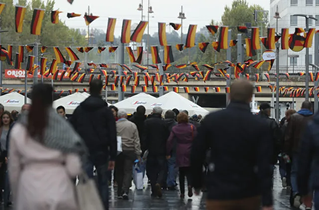 DRESDEN, GERMANY - OCTOBER 03: People walk under Germn flags fluttering above in the city center during celebrations to mark German Unity Day on October 3, 2016 in Dresden, Germany. Unity Day, called Tag der Deutschen Einheit, commemorates German reunification of East and West Germany following the end of the Cold War. This year's main celebrations are taking place in Dresden and are being accompanied by protests from both left and right-wing groups, notably the anti-Muslim and anti-immigration Pegida movement, which has its roots in Dresden, as well as extraordinary security measures by police. (Photo by Sean Gallup/Getty Images)