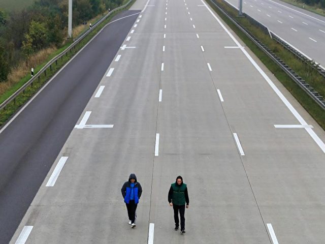 Zwei Fußgänger laufen auf der leeren A2 am Rasthof Börde. Foto: Peter Gercke/dpa