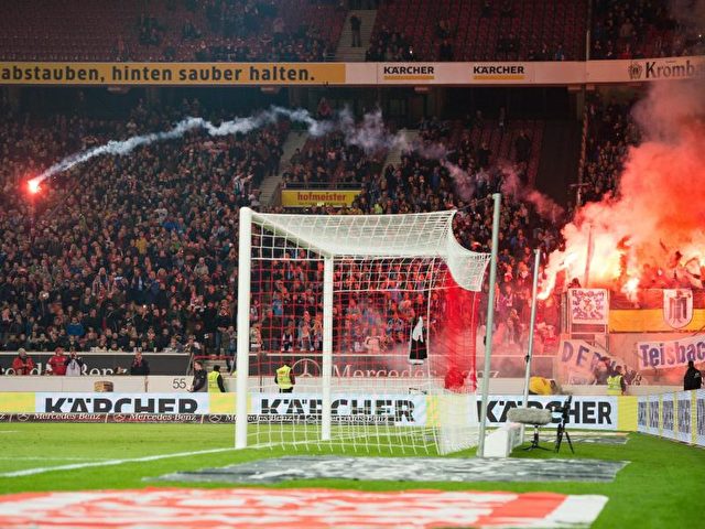 Fans von TSV 1860 München Fans werfen aus ihrem Block in Stuttgart Pyrotechnik auf das Spielfeld. Foto: Deniz Calagan/dpa
