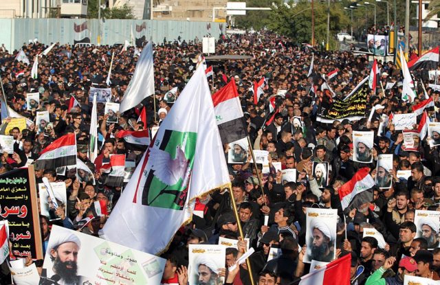 Supporters of Iraqi Shiite cleric Moqtada al-Sadr wave their national flag and hold posters of prominent Shiite cleric Nimr al-Nimr during a demonstration in the capital Baghdad on January 4, 2016, against Nimr's execution by Saudi authorities. Sunni-ruled Saudi Arabia severed diplomatic ties with Shiite-dominated Iran, its long-time regional rival, after angry demonstrators attacked the Saudi embassy in Tehran and its consulate following Nimr's execution. AFP PHOTO / AHMED AL-RUBAYE / AFP / Ahmad al-Rubaye (Photo credit should read AHMAD AL-RUBAYE/AFP/Getty Images)