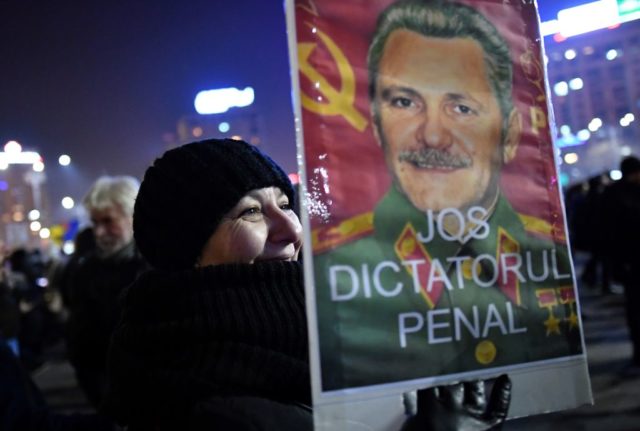 A woman holds a make-up poster of Liviu Dragnea, the leader of Social Democrat Party (PSD) rulling party made to look as Stalin reading "Down with criminal dictator" during a protest against controversial decrees to pardon corrupt politicians and decriminalize other offenses in front of the government headquarters in Bucharest, on February 1, 2017. At least 200,000 people hit the streets across Romania on February 1, 2017 for anti-government protests, the largest since communism fell in 1989, media reports said. / AFP / DANIEL MIHAILESCU (Photo credit should read DANIEL MIHAILESCU/AFP/Getty Images)