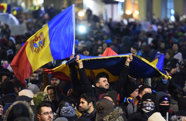People wave flags during a protest in front of the government headquarters in Bucharest against controversial decrees to pardon corrupt politicians and decriminalize other offenses on February 1, 2017. Hundreds of thousands of people hit the streets across Romania on February 1 to protest against the government's decriminalising of a string of corruption offences, the largest demonstrations since the fall of communism in 1989. / AFP / DANIEL MIHAILESCU (Photo credit should read DANIEL MIHAILESCU/AFP/Getty Images)