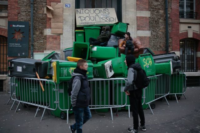 Students stand on a barricade made with dustbins as they protest against police brutality, following the alleged rape of Theo, outside the "Lycee Dorian" secondary school in Paris, on February 23, 2017. / AFP / GEOFFROY VAN DER HASSELT (Photo credit should read GEOFFROY VAN DER HASSELT/AFP/Getty Images)