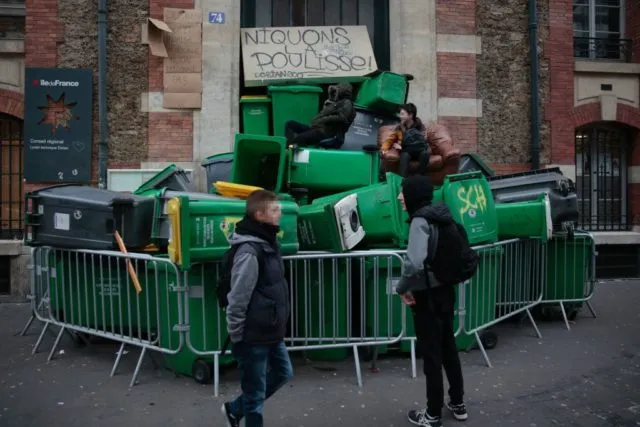 Students stand on a barricade made with dustbins as they protest against police brutality, following the alleged rape of Theo, outside the &quot;Lycee Dorian&quot; secondary school in Paris, on February 23, 2017. / AFP / GEOFFROY VAN DER HASSELT (Photo credit should read GEOFFROY VAN DER HASSELT/AFP/Getty Images)