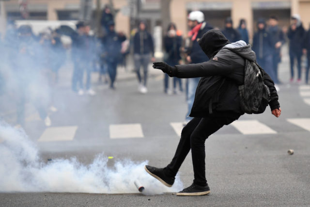 A man kicks away a smoke grenade launched by riot police during a protest of students against police brutality, following the alleged rape of Theo, next to the "Lycee Voltaire" secondary school in Paris, on February 23, 2017. / AFP / Lionel BONAVENTURE (Photo credit should read LIONEL BONAVENTURE/AFP/Getty Images)