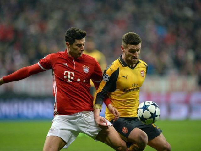 Robert Lewandowski (l) kämpft gegen Shkodran Mustafi vom FC Arsenal um den Ball. Foto: Andreas Gebert/dpa