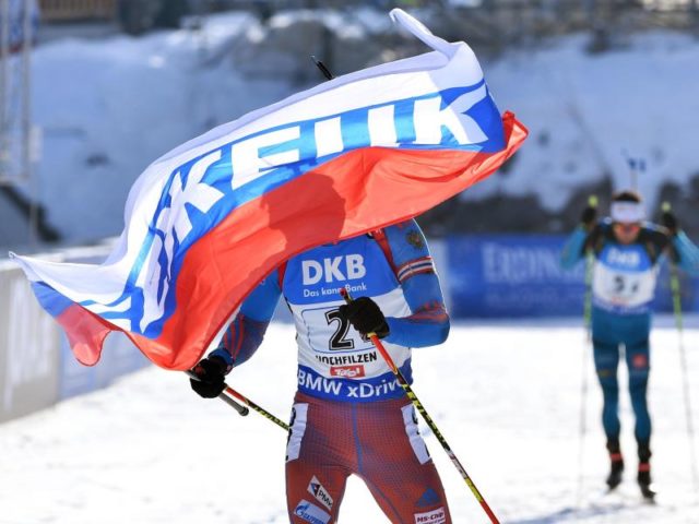 Russlands Schlussläufer Anton Schipulin (l) jubelt mit der Landesfahne im Ziel über WM-Gold. Foto: Martin Schutt/dpa