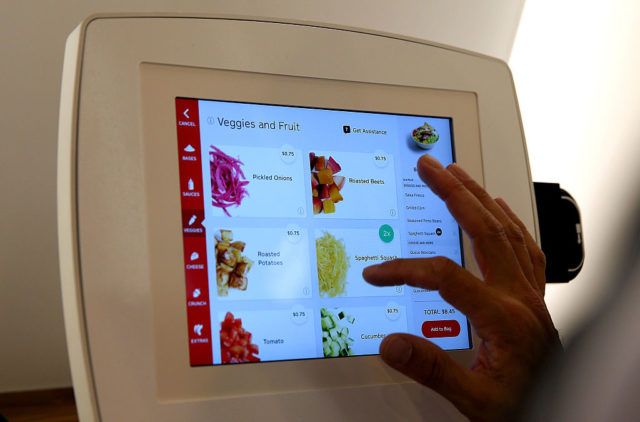 SAN FRANCISCO, CA - AUGUST 31: A customer uses an interactive kiosk to place orders at eatsa, a fully automated fast food restaurant on August 31, 2015 in San Francisco, California. eatsa, an automated fast food restaurant that has no servers, wait staff and a virtual cashier that offers fresh quinoa bowls opened in San Francisco's Financial District. Customers place their orders at an interactive kiosk and then pick their orders at a first of its kind automated food pick-up system that features a collection of glass door "cubbies" with a door that displays personalized graphics and presents the food at the touch of a button. (Photo by Justin Sullivan/Getty Images)