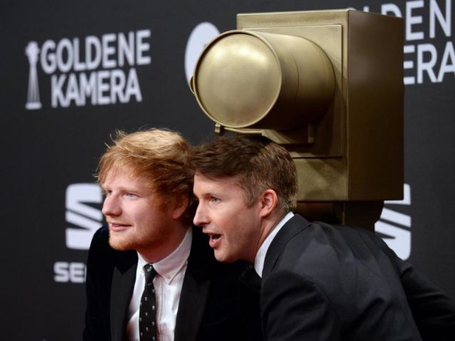 Die britischen Sänger Ed Sheeran (l) und James Blunt posierenderweise. Foto: Daniel Reinhardt/dpa