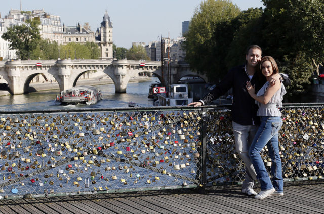 A couple poses on the "Pont des Arts" bridge in front of love locks on September 6, 2012 in Paris. AFP PHOTO / PATRICK KOVARIK (Photo credit should read PATRICK KOVARIK/AFP/GettyImages)