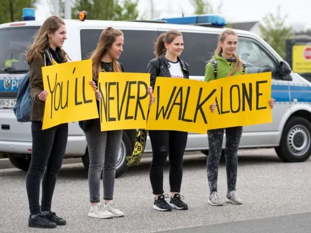 Fans halten vor dem Trainingsgelände von Borussia Dortmund Schilder mit der Aufschrift «You'll never walk alone». Foto: Marius Becker/dpa