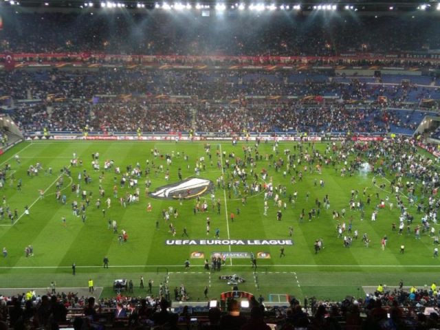 Ajax-Fans flüchten sich vor Feuerwerkskörpern auf das Spielfeld. Foto: Depo Photos/dpa