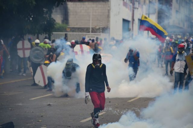 Demonstranten in Wolken von Tränengas, das von der Polizei abgeschoßen wurde. Foto: RONALDO SCHEMIDT/AFP/Getty Images