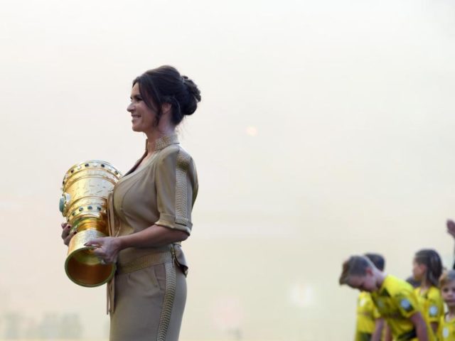 Eiskunstlauf-Legende Katharina Witt trägt die DFB-Pokal-Trophäe ins Stadion. Foto: Arne Dedert/dpa