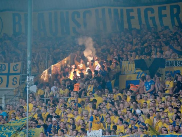 Braunschweiger Fans brennen auf der Tribüne Feuerwerkskörper ab. Foto: Peter Steffen/dpa