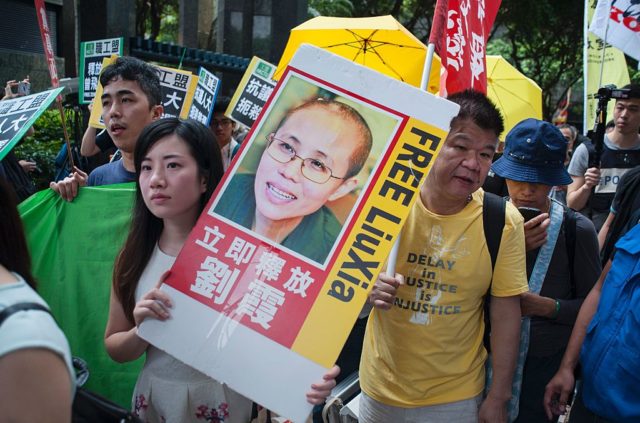 A protester (centre L) holds a placard calling for the release of Chinese human rights activist Liu Xiaobo (pictured C) as she joins a march in the Wanchai district of Hong Kong on May 18, 2016 calling for universal suffrage and an end to arrests of activists in China as a top Beijing official visits the city. The protest coincided with three-day trip by Zhang Dejiang, who chairs China's communist-controlled legislature, and is the first by such a senior official in four years and comes as concerns grow that freedoms are under threat in semi-autonomous city. / AFP / Richard A. Brooks (Photo credit should read RICHARD A. BROOKS/AFP/Getty Images)