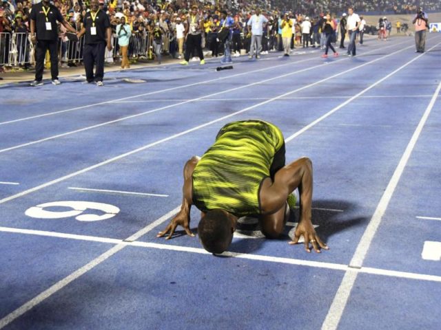 Usain Bolt küsst nach seinem Sieg beim «Racers Grand Prix» zum Abschied die Ziellinie der Tartanbahn in Kingston. Foto: Bryan Cummings/dpa