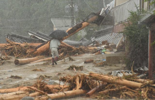 TOPSHOT - A resident walks past collapsed houses following heavy flooding in Asakura, Fukuoka prefecture, on July 7, 2017. Huge floods engulfing parts of southern Japan are reported to have killed at least six people and left hundreds stranded as the torrents swept away roads and houses and destroyed schools. / AFP PHOTO / KAZUHIRO NOGI (Photo credit should read KAZUHIRO NOGI/AFP/Getty Images)