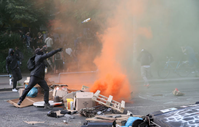 A protester throwa a bottle at Police on July 7, 2017 in Hamburg, northern Germany, where leaders of the world's top economies gather for a concert on the sidelines of a G20 summit. Protesters clashed with police and torched patrol cars in fresh violence ahead of the G20 summit, police said. German police and protestors had clashed already the day before at an anti-G20 march, with police using water cannon and tear gas to clear a hardcore of masked anti-capitalist demonstrators, AFP reporters said. / AFP PHOTO / Ronny HARTMANN (Photo credit should read RONNY HARTMANN/AFP/Getty Images)