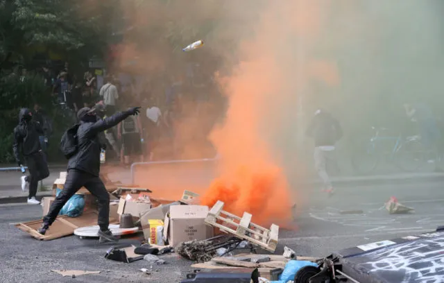 A protester throwa a bottle at Police on July 7, 2017 in Hamburg, northern Germany, where leaders of the world's top economies gather for a concert on the sidelines of a G20 summit. Protesters clashed with police and torched patrol cars in fresh violence ahead of the G20 summit, police said. German police and protestors had clashed already the day before at an anti-G20 march, with police using water cannon and tear gas to clear a hardcore of masked anti-capitalist demonstrators, AFP reporters said. / AFP PHOTO / Ronny HARTMANN (Photo credit should read RONNY HARTMANN/AFP/Getty Images)