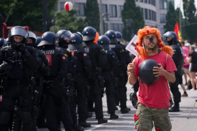 A protester walks by riot police on July 7, 2017 in Hamburg, northern Germany, where leaders of the world's top economies gather for a G20 summit. Protesters clashed with police and torched patrol cars in fresh violence ahead of the G20 summit, police said. German police and protestors had clashed already the day before at an anti-G20 march, with police using water cannon and tear gas to clear a hardcore of masked anti-capitalist demonstrators, AFP reporters said. / AFP PHOTO / STEFFI LOOS (Photo credit should read STEFFI LOOS/AFP/Getty Images)