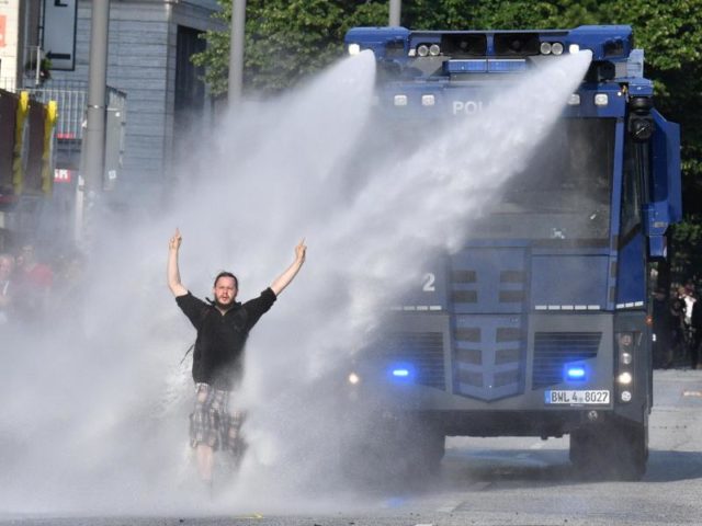 Ein Demonstrant stellt sich im Bereich der Reeperbahn in Hamburg einem Wasserwerfer entgegen. Foto: Boris Roessler/dpa