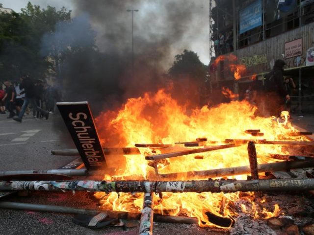 Verwüstung, Zerstörung, Gewalt. Ein herausgerissenes Straßenschild liegt in den Flammen. Foto: Markus Scholz/dpa