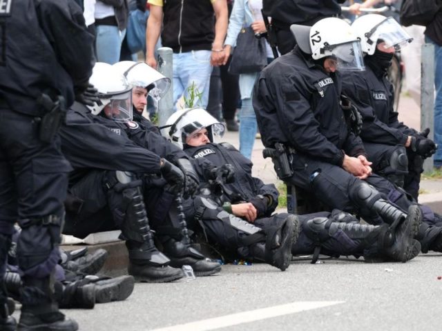 Völlig erledigt: Polizisten ruhen sich am Rande der Demonstration «Grenzenlose Solidarität statt G20» aus. Foto: Sebastian Willnow/dpa