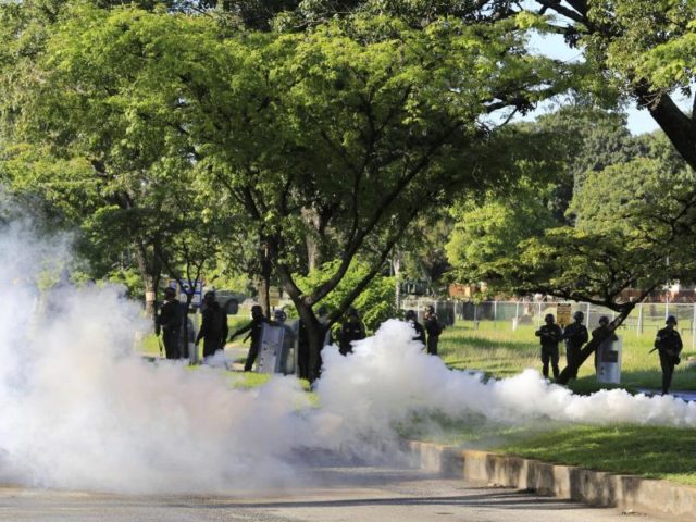 Mitglieder der Nationalgarde werfen Tränengas gegen Demonstranten, die zu der Kaserne Paramacay in Valencia marschieren. Foto: Juan Carlos Hernandez/dpa