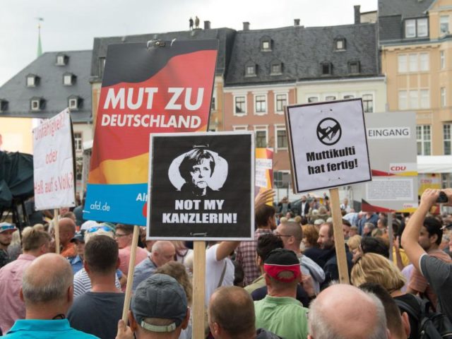 Protestler stehen während eines Wahlkampfauftritts von Bundeskanzlerin Merkel auf dem Marktplatz in Annaberg-Buchholz. Foto: Sebastian Kahnert/dpa