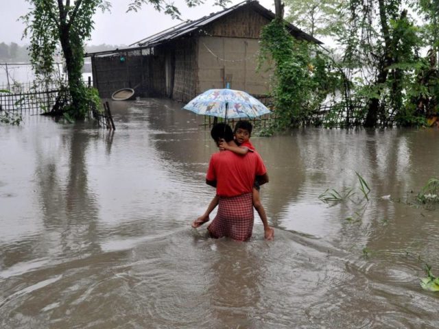 Ein Vater trägt in Lakhimpur (Indien) seinen Sohn. Allein in Indien sind mehr als 1000 Menschen im Zusammenhang mit der Regenzeit ums Leben gekommen. Foto: akhimpur- Dasarath Deka/PTI/dpa