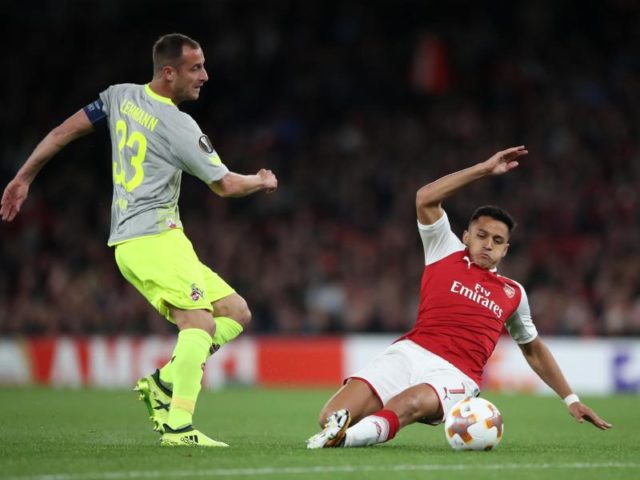 Arsenals Alexis Sanchez (r) versucht den Kölner Kapitän Matthias Lehmann vom Ball zu trennen. Foto: Nick Potts/dpa