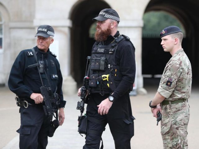 Bewaffnete Polizisten und ein Soldat sichern den Eingang zu Horse Guards in Whitehall in London. Foto: Jonathan Brady/dpa
