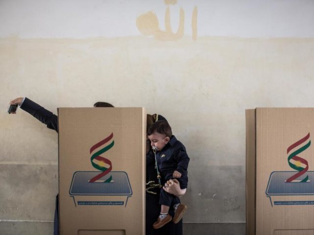 Ein Mann fotografiert sich in Erbil mit seiner Familie in einer Wahlkabine. Foto: Oliver Weiken/dpa